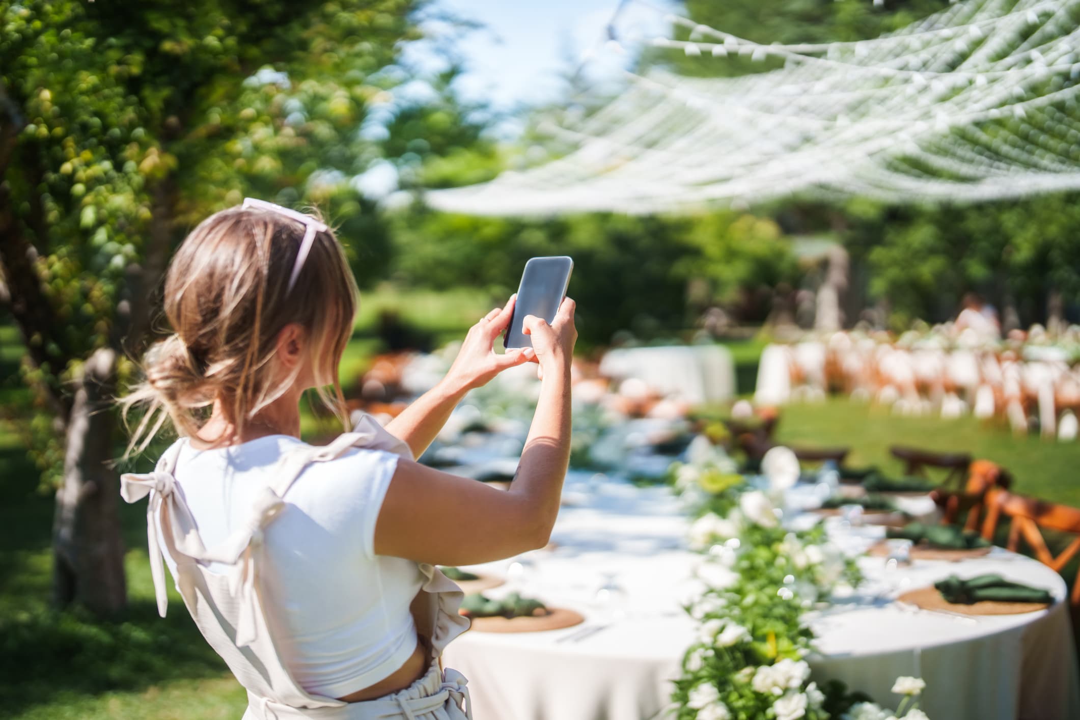 A content creator photographs a wedding reception table with a phone